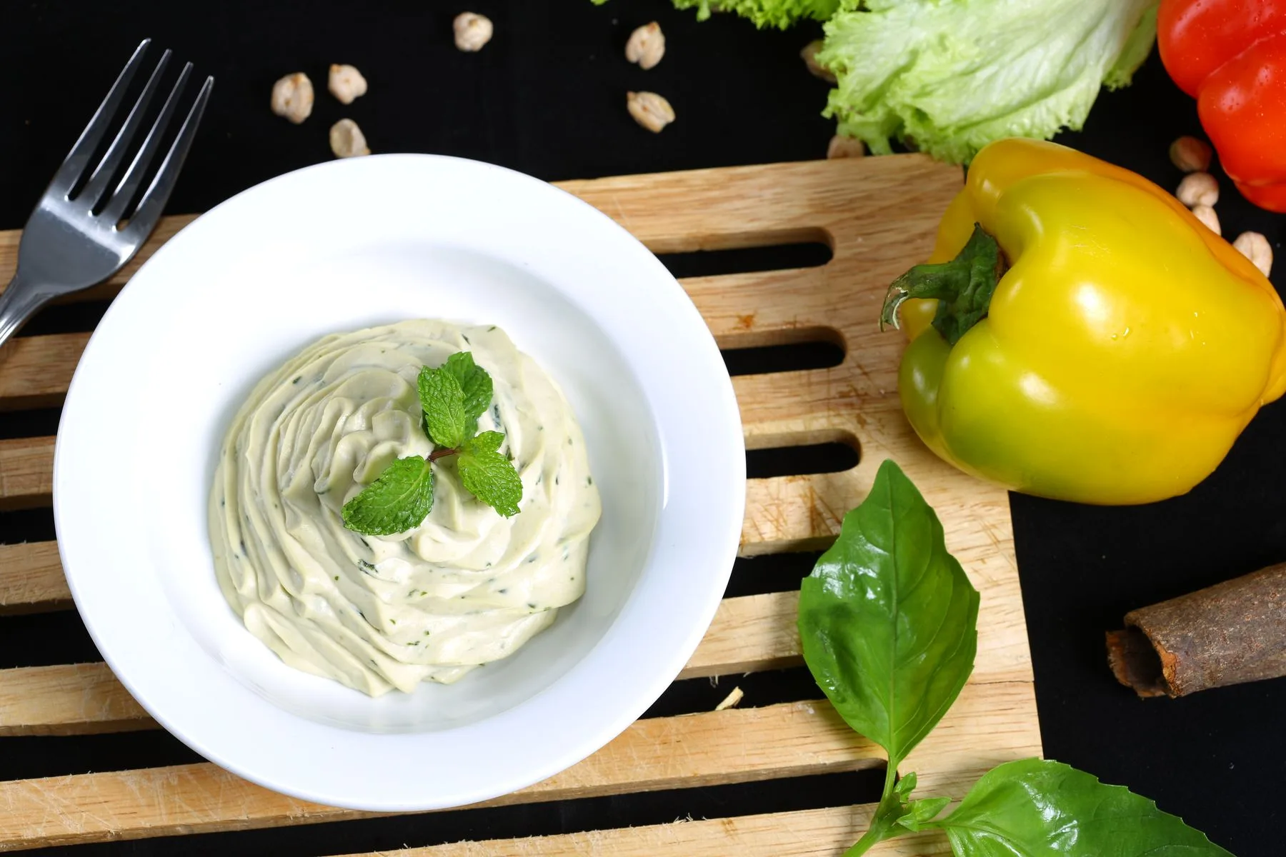 En lys urtedip i en hvit skål sammen med paprika og salat