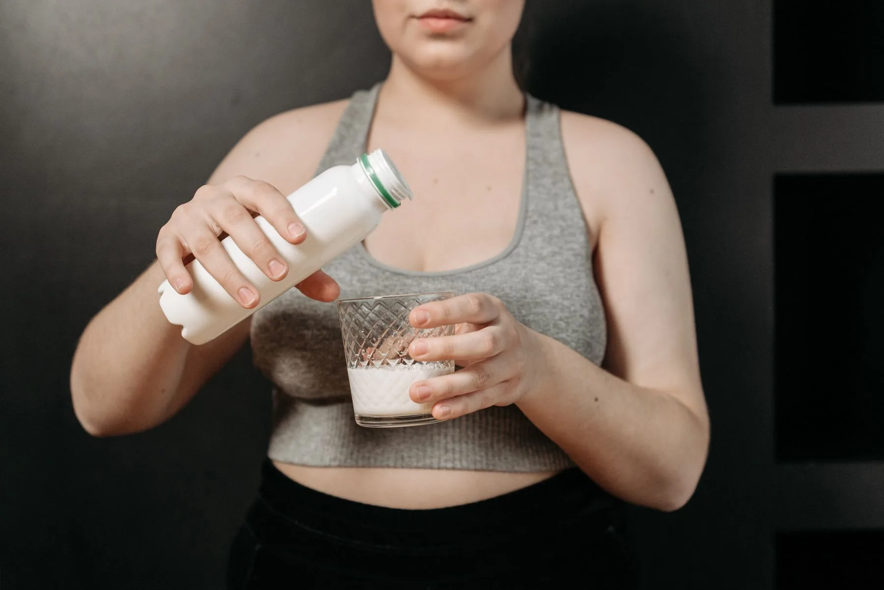 En person heller melk fra en umerket flaske over i et glass