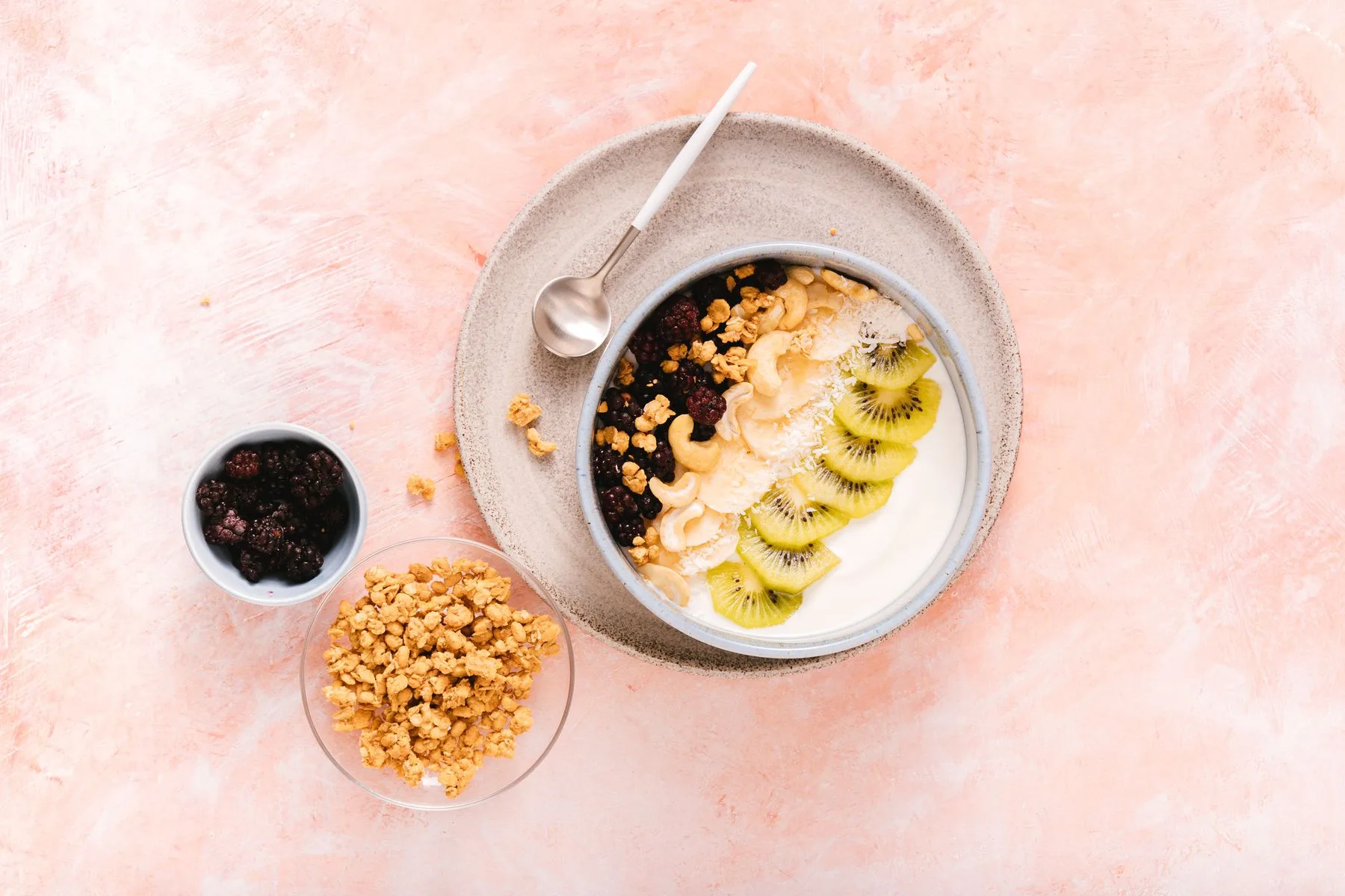 En skål med tykt syrnet melkeprodukt, kiwi, bær, cashewnøtter og müsli